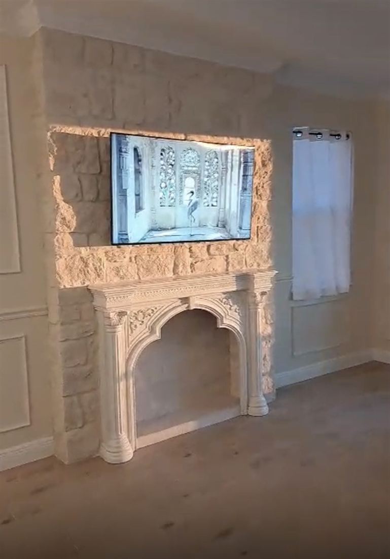 Carved white stone fireplace surround beneath a wall-mounted TV