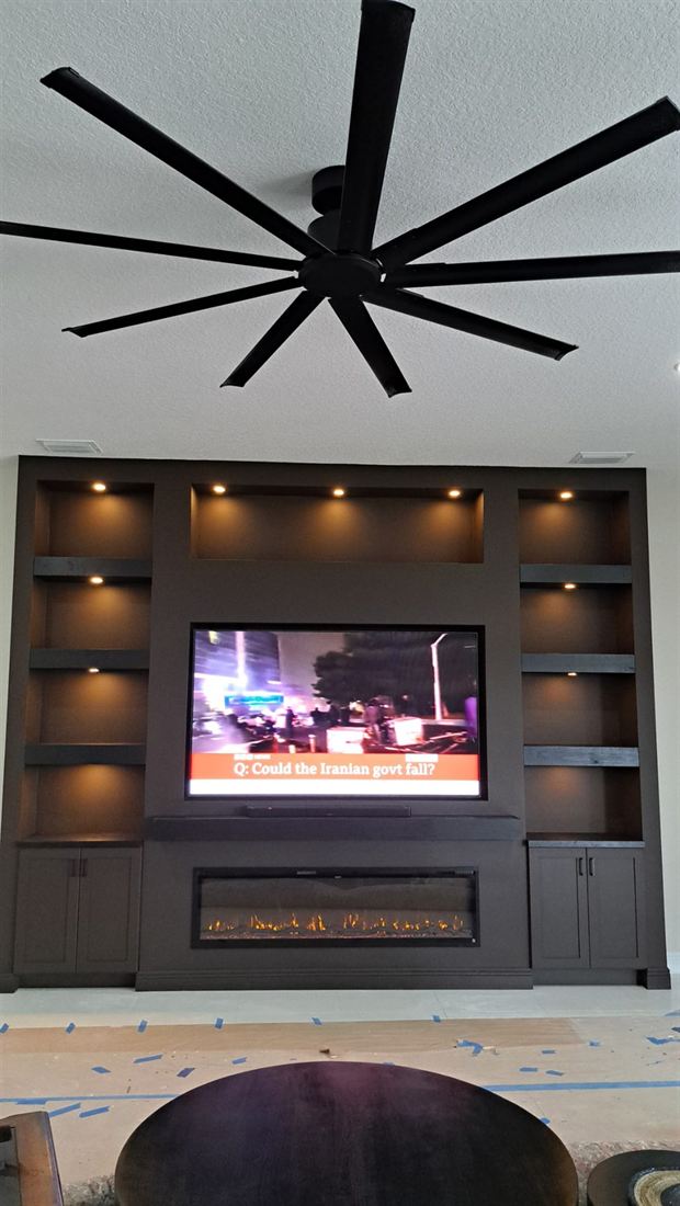 Espresso built-in entertainment center with warm lighting and base cabinets