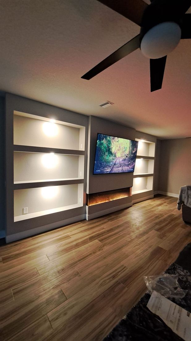 Recessed media wall with lit shelves and electric fireplace