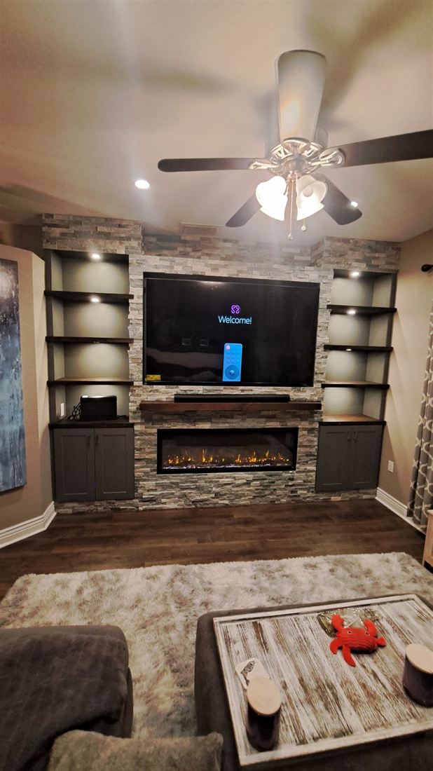Stone media wall with charcoal cabinetry and glowing shelves