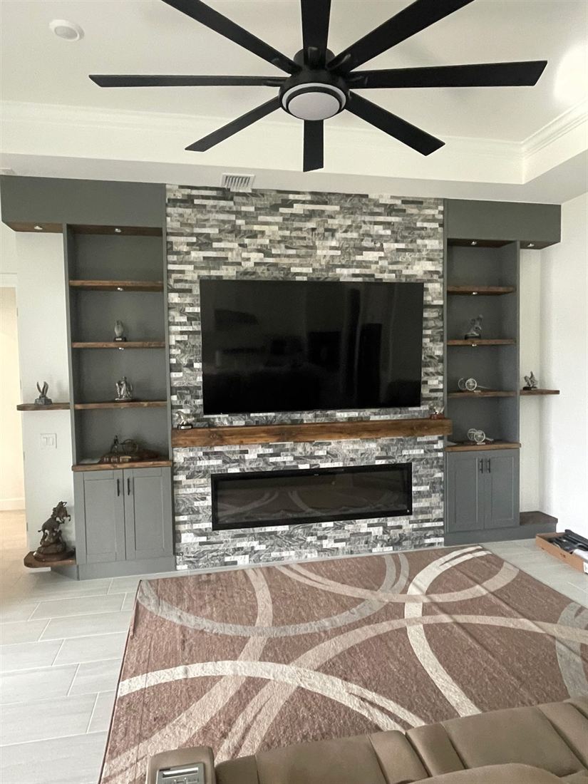 Stone-faced media wall with a wood mantel, linear fireplace and built-in shelving